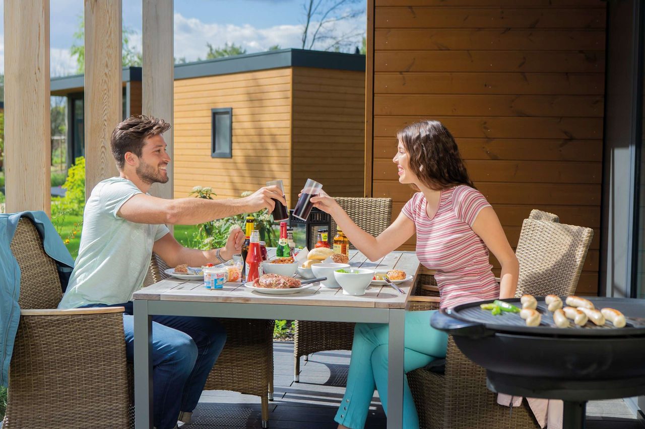 Couple barbecues on vacation home terrace